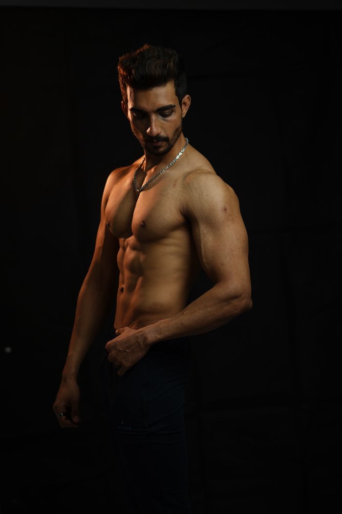 gallery-3 Shirtless muscular man posing in a dark studio with dramatic lighting.