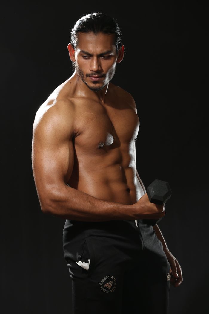 services-03 Athletic man demonstrating strength by lifting a dumbbell during a studio photoshoot.