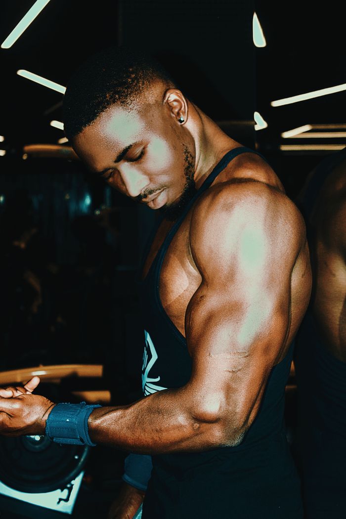 our-experience Black man demonstrating muscular physique in gym, highlighting strength and fitness.