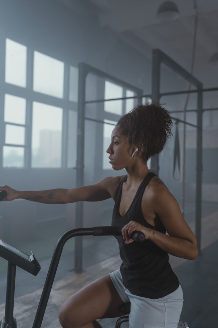 gallery-2 African American woman intensely working out using gym equipment indoors.
